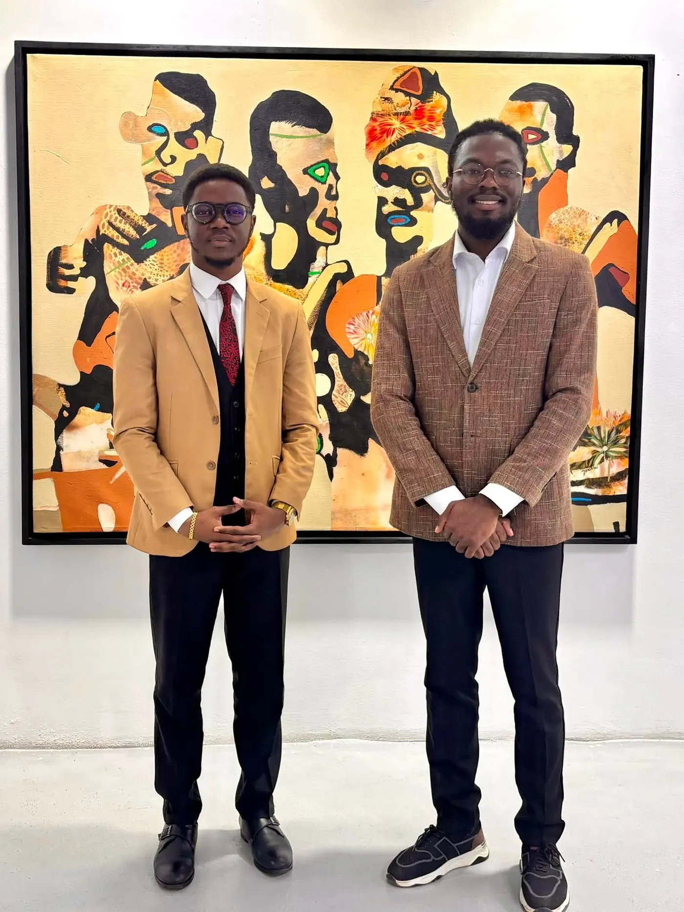 Deux hommes posent devant un tableau dans une galerie.